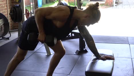 tattoo man muscles in home gym doing right arm bent over lat pull