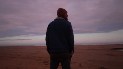 a man stands and looks out to the ocean in australia with beautiful pink clouds in the morning sunrise