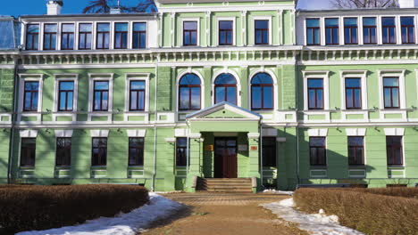 reveal backwards dolly of kokmuiža manor complex, beautiful green villa in latvia with latvian flag atop