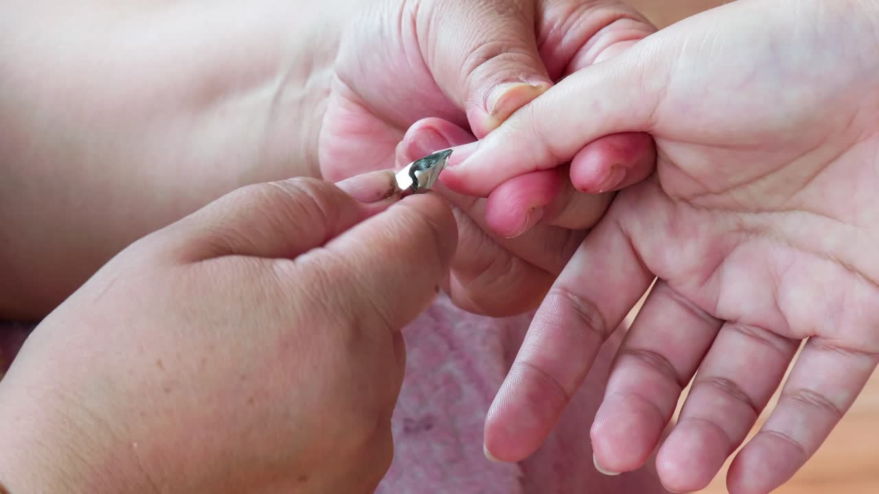 Pedicurist master making manicure cutting cuticle with nail tongs on client's toes in a beauty salon