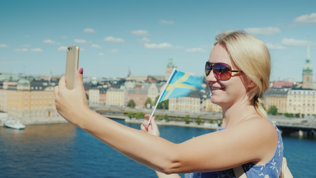 счастливый турист с флагом швеции фотографирует себя на фоне стокгольма".