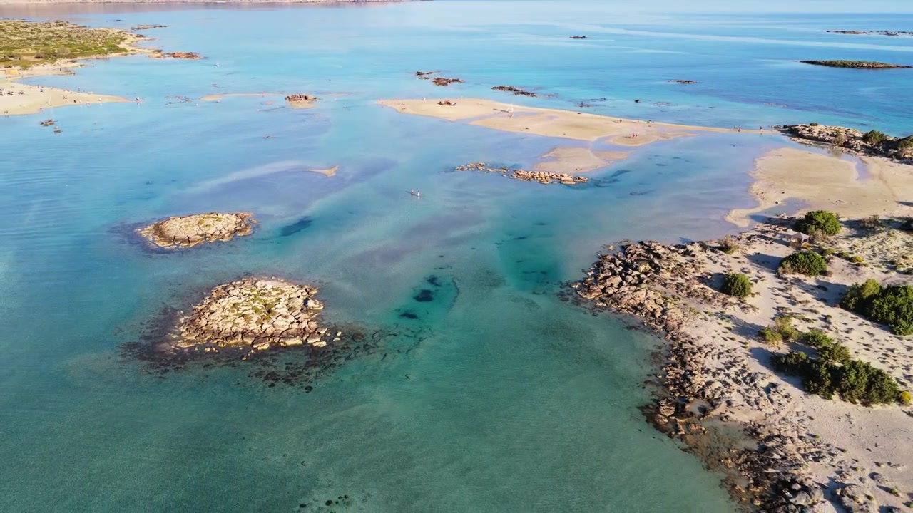 Vista aerea con drone di isolotti rocciosi e scogliere in una laguna turchese accanto a banchi di sabbia chiari, Elafonissi, Grecia