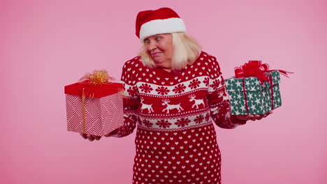 abuela mayor mujer en suéter de navidad sostiene dos cajas de regalos en las manos, compras vacaciones venta