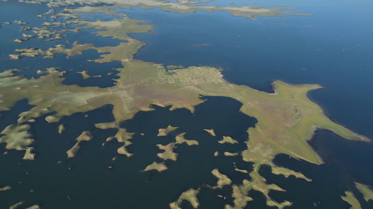 Aerial shot of Karamchat Dam, with a river winding through the lush forest and open fields.