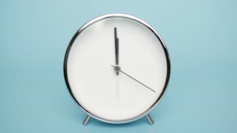 silver wall clock on a blue background, showtime 11.59 am.