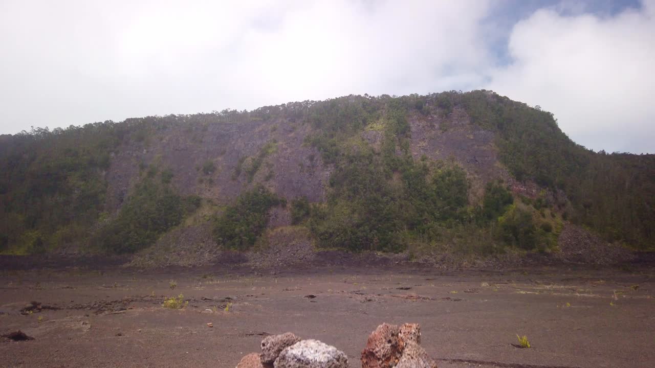 Gimbal booming up shot over trail cairn to reveal the steep slopes of the Kilauea Iki crater in Hawai'i Volcanoes National Park