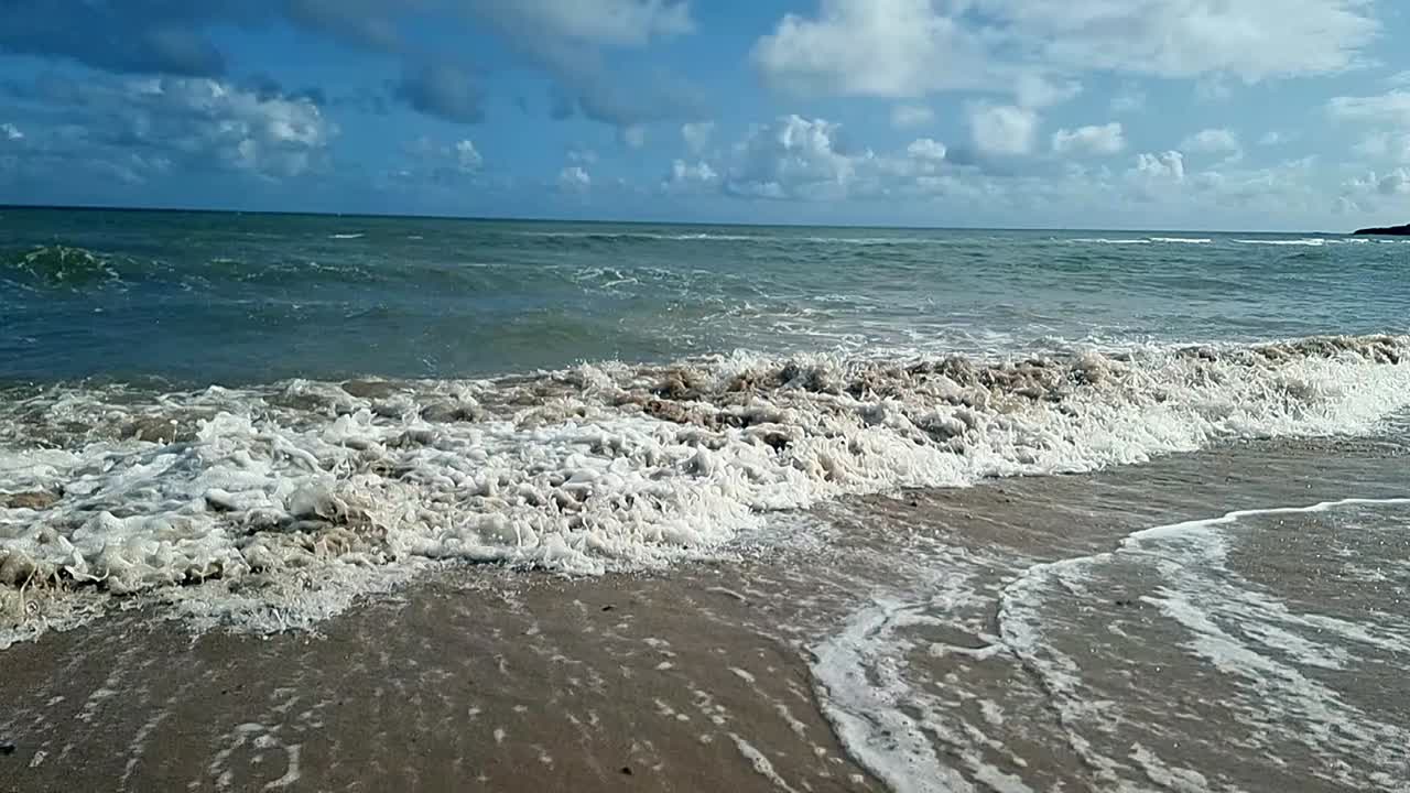 las olas del océano en cámara lenta salpican sobre la pintoresca playa de arena de la isla cielo azul romántica costa tropical