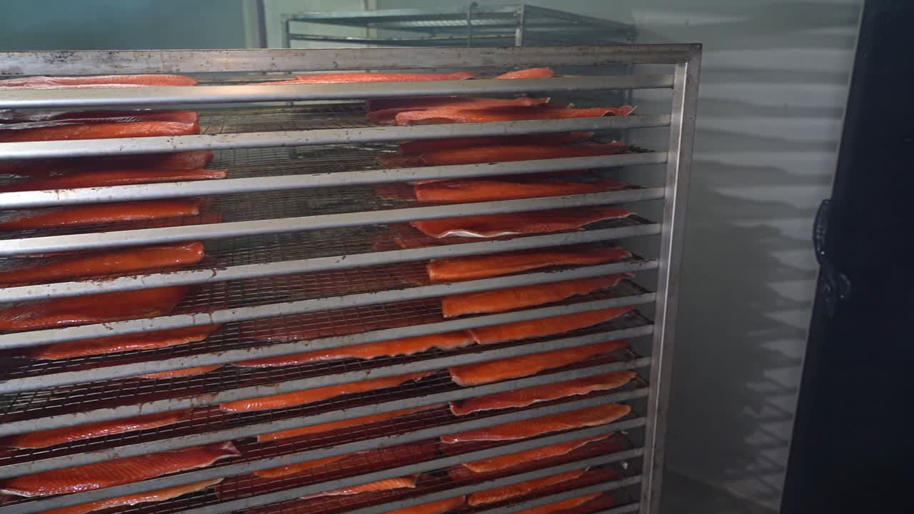 Operaio dell'industria ittica che movimenta un carrello pieno di salmone all'interno di un affumicatoio - Rallentatore