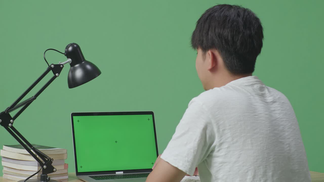 초록색 화면의 노트북에서 공부하는 사람