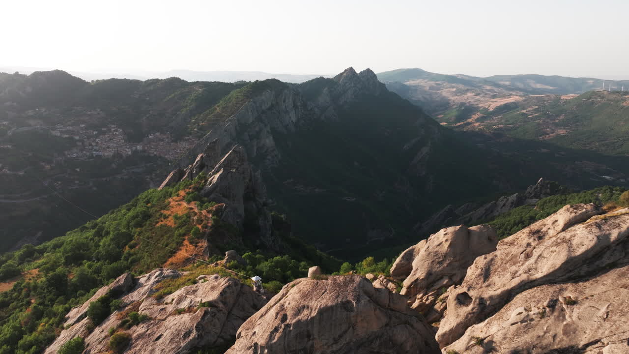 Aerial drone of Pietrapertosa, Italy—mountain village built into rocky peaks, terracotta roofs, sweeping valley views. Ideal for travel, tourism, culture, and cinematic landscape stock footage