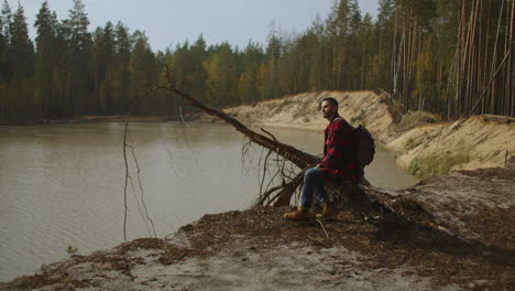 en un paseo. un excursionista caminando en un bosque. un turista con capucha negra vestido y de pie en el muelle del lago cinematográfico en una fría mañana de primavera. toma de inspiración. imágenes de alta calidad 4k