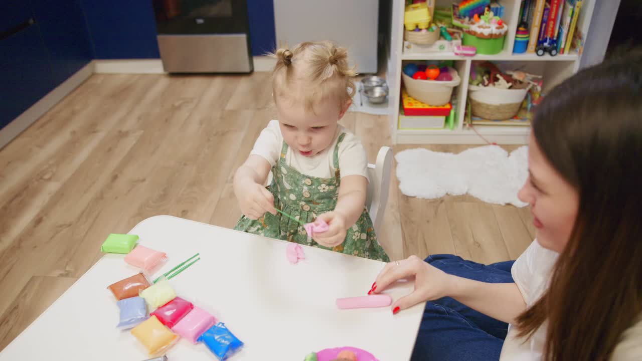 Renkli oyun hamuruyla oynayan küçük kız çocuğu ve anne