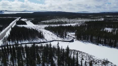 Rotating-aerial-overview-of-small-river-bend-in-the-middle-of-snowy-coniferous-forest-in-Sweden