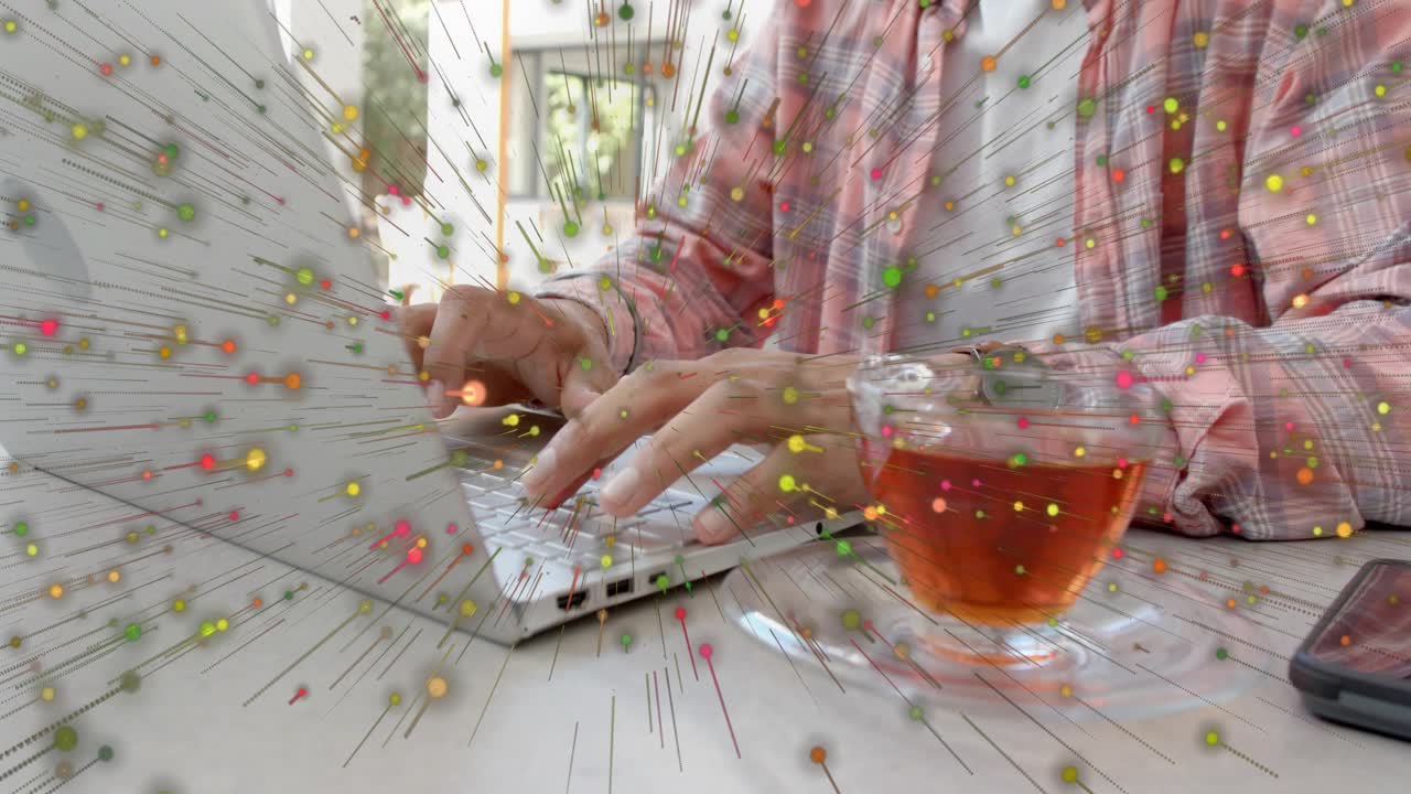 Man pressing keys and typing on laptop at table for business, particle dots radiating around hands