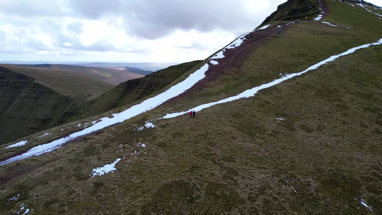 Hiking couple reaching Pen y Fan highest peak in South Wales, aerial