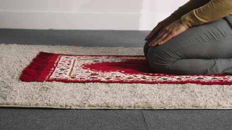 hombre musulmán en casa arrodillado sobre una alfombra de oración y orando 1