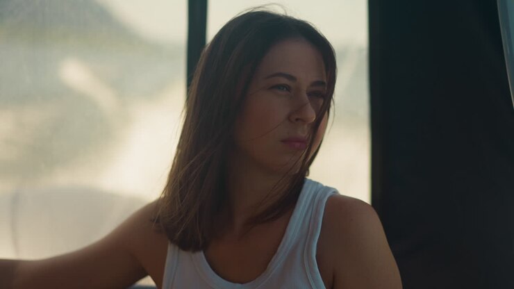 Attractive woman looks back at foamy trail riding motorboat at sea tour. Relaxed lady enjoys yacht sailing on summer holiday. Passenger comfort