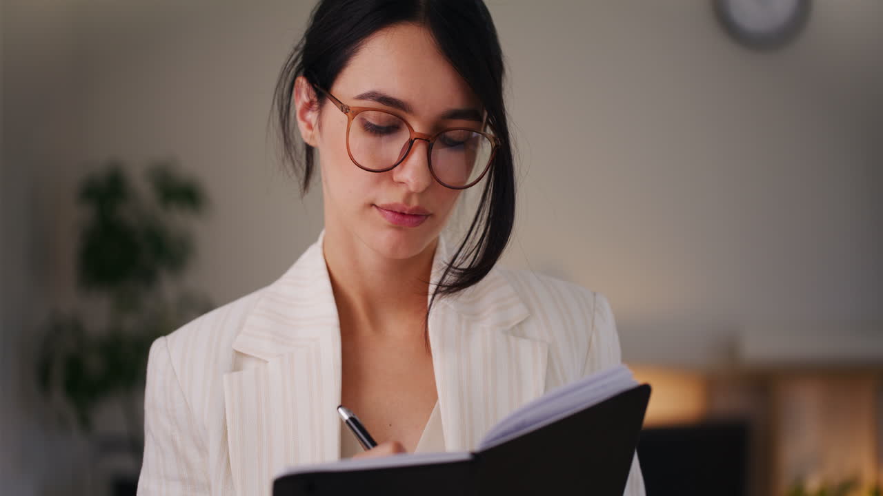 mujer escribiendo en un cuaderno, planeando reuniones con clientes