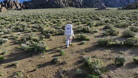 Aerial-tilt-shot-following-an-space-traveller-walking-across-desert-nature