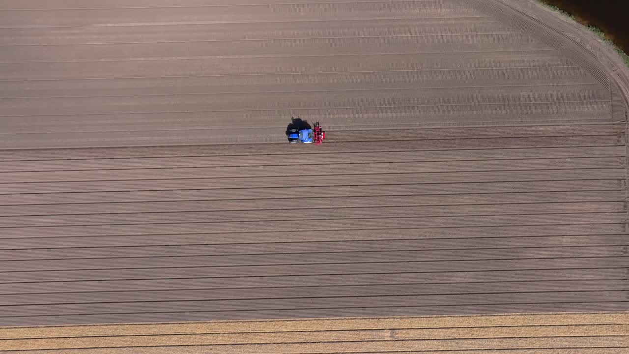 Vista aerea di macchinari agricoli che seminano colture attraverso un prato olandese