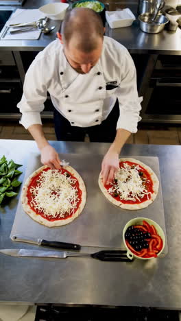 chef prepares pizzas in a commercial kitchen