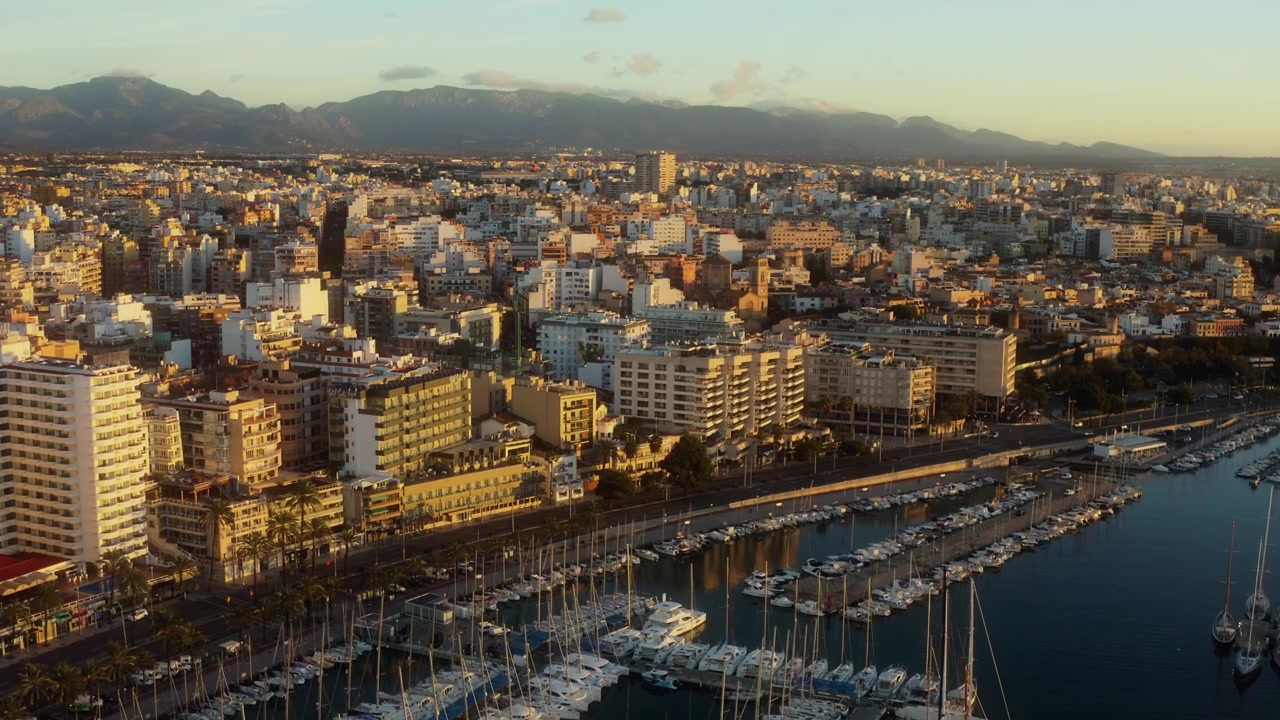 Drone in volo sorvola la marina della costa di Palma e la fitta città sotto colline distanti