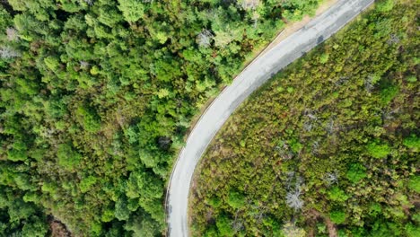 winding narrow asphalt road through mountain range, drone top view