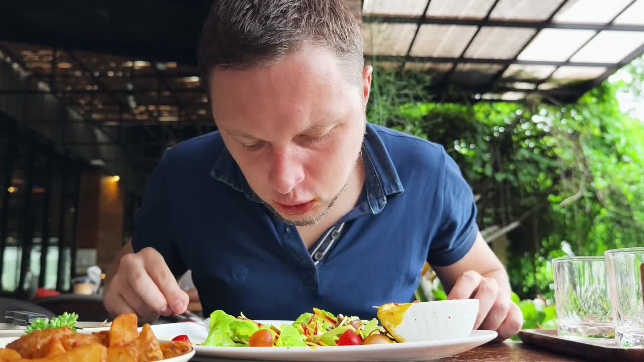 hombre comiendo ensalada en un restaurante