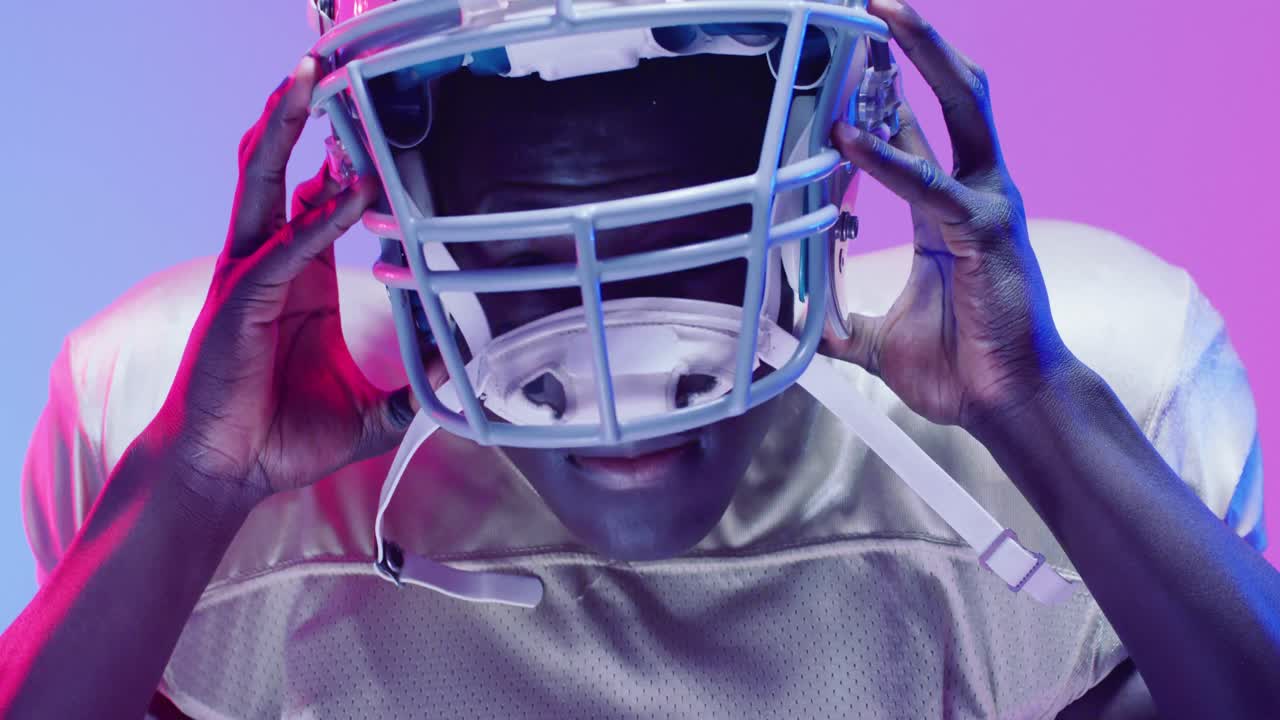 Video ritratto di un giocatore di football americano afroamericano su sfondo neon da blu a rosa