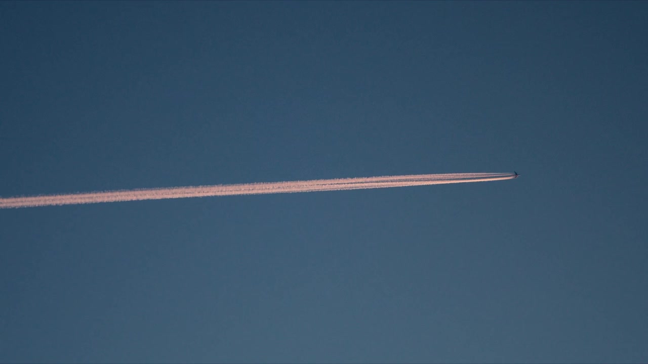 Jejak kondensasi pesawat tipis membentang di langit Arktik biru yang tenang di Norwegia