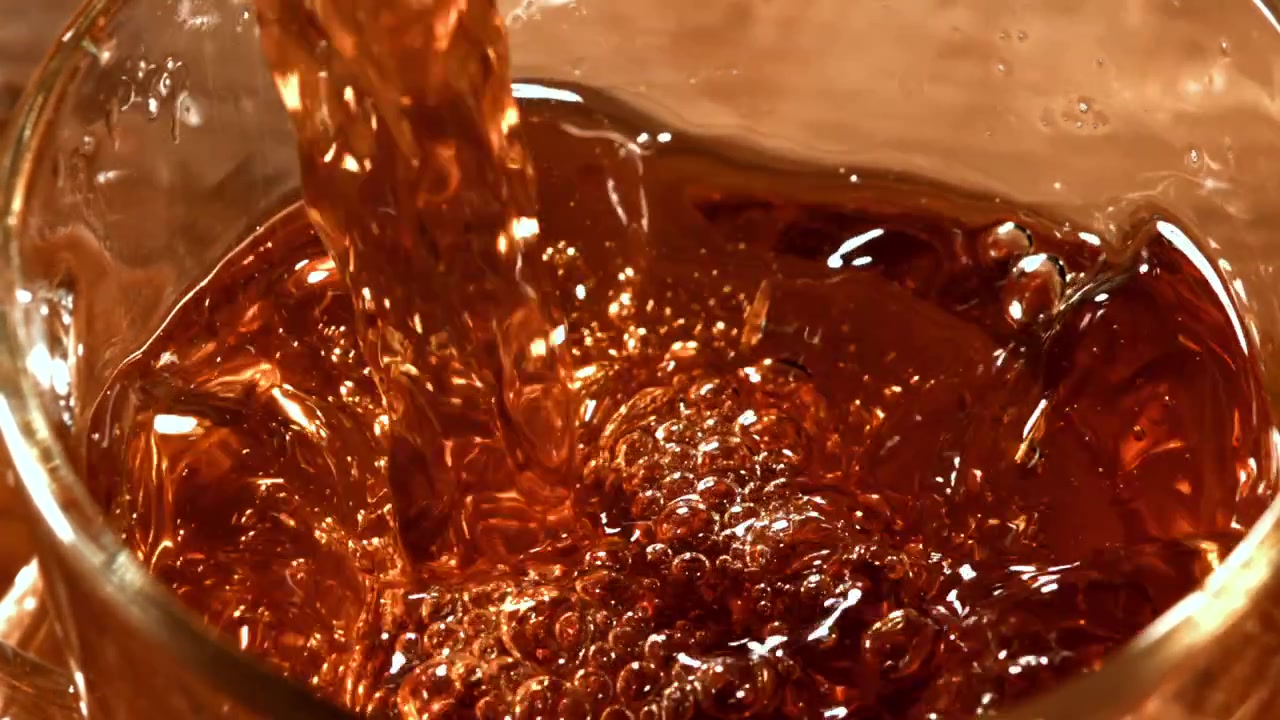 Vertido en cámara lenta de líquido ámbar en un vaso.