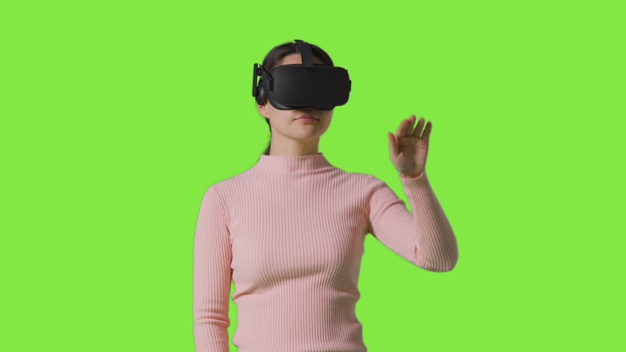 mujer con auriculares de realidad virtual e interactuando contra el fondo del estudio de pantalla verde