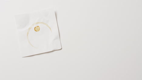 video de primer plano de un pedazo de papel con una taza de café mancha de anillo sobre fondo blanco con espacio de copia