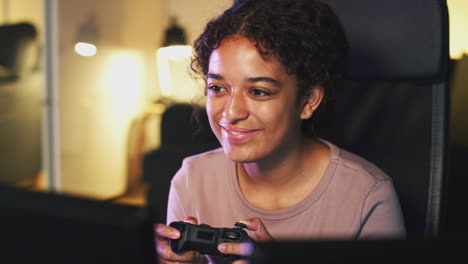 teenage girl sitting in chair in front of screen at home holding computer controller and gaming