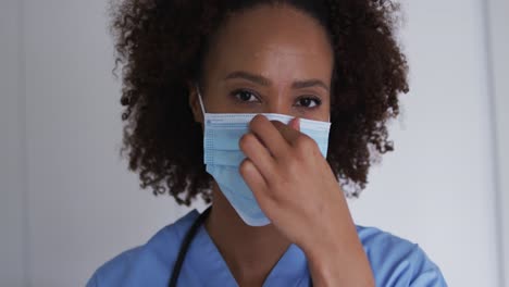 Portrait-of-mixed-race-female-doctor-wearing-mask-and-looking-at-camera