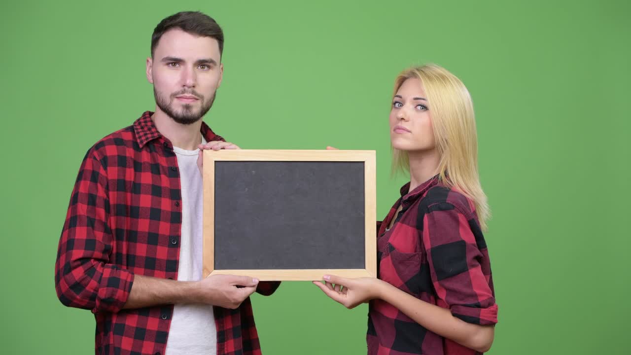 Young couple holding blackboard together