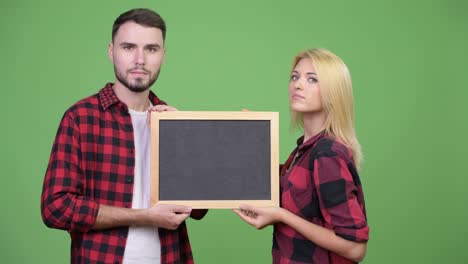 young couple holding blackboard together