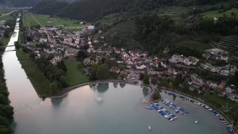 aerial drone view flying forward of weesen town based near shore of walensee lake, switzerland