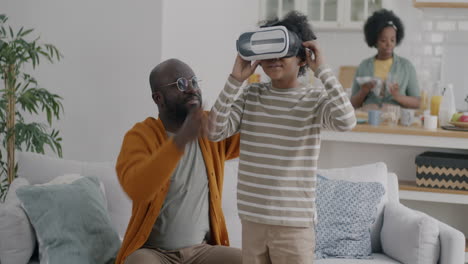 father and son playing with vr headset at home