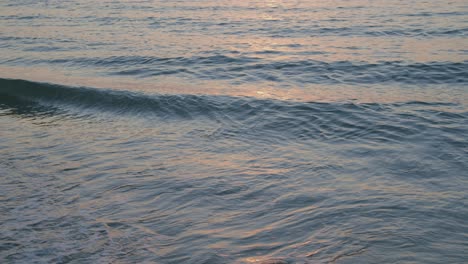 waves crashing on a beach during sunset - wide shot