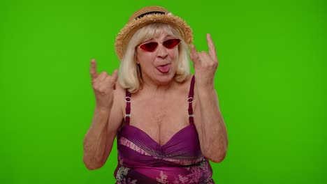 Senior-woman-tourist-in-swimsuit-dancing,-celebrating,-showing-tongue,-rock-and-roll-hand-gesture