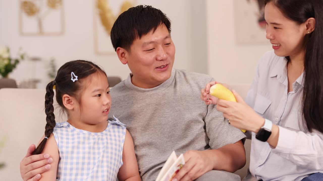 A joyful family shares a moment peeling and eating bananas in a cozy living room setting