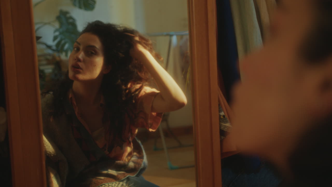 Ragazza che si tocca i capelli e si esamina allo specchio a casa.