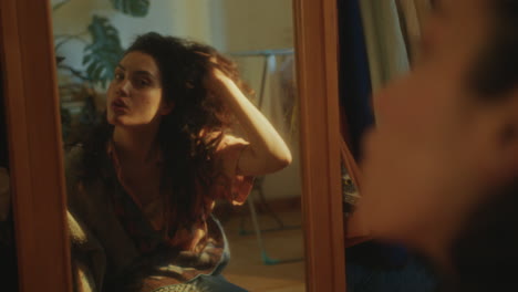 young girl touching hair and examining reflection in mirror at home