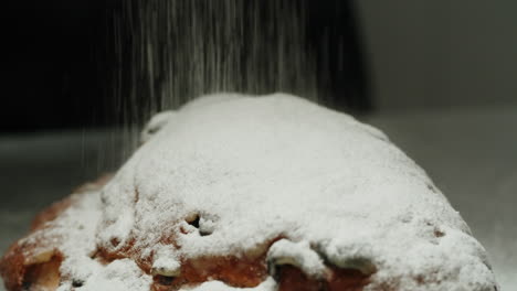 sprinkling powdered sugar on a christmas stollen