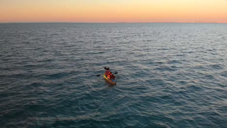 Un-Par-De-Kayak-En-Aguas-Profundas-Reflectantes-Del-Océano-Durante-La-Magnífica-Puesta-De-Sol-Naranja