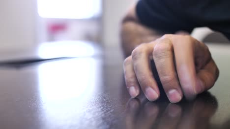 mano golpeando nerviosamente la mesa y apuntando con el dedo hacia un lado