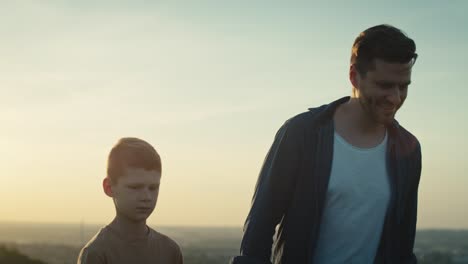 un niño caminando con su padre en el prado durante la puesta de sol.
