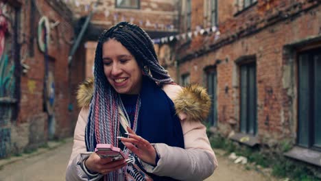 woman with braids using phone in a city alley