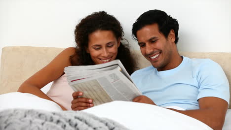 couple in the bed reading a newspaper